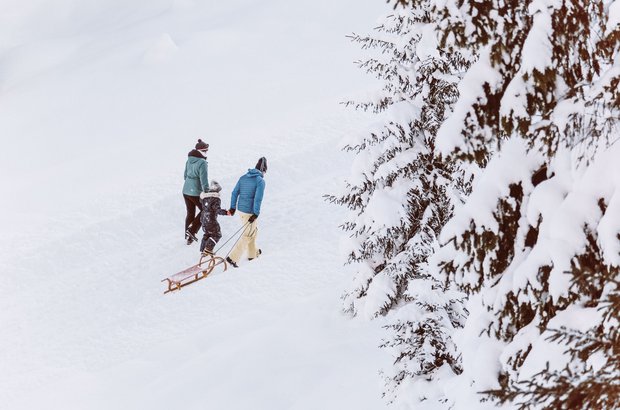 Familie zieht Ihren Schlitten den Wanderweg entlang. 