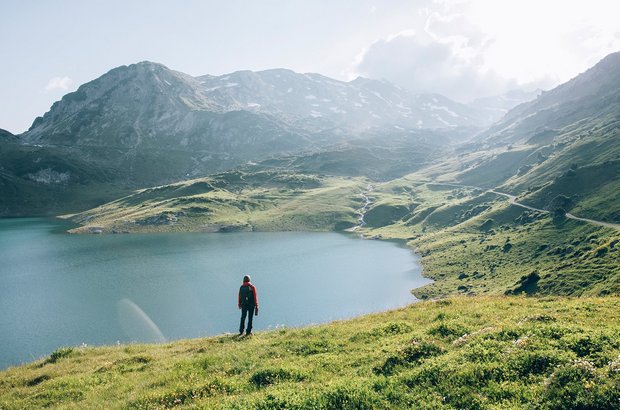 Wandern am Formarinsee Ein Wanderer steht vor dem Formarinsee und blickt auf die dahinterliegende Berwelt.