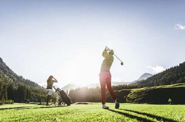 Golf in Lech am Arlberg Ein Golfspieler schwingt seinen Schläger nach hintern