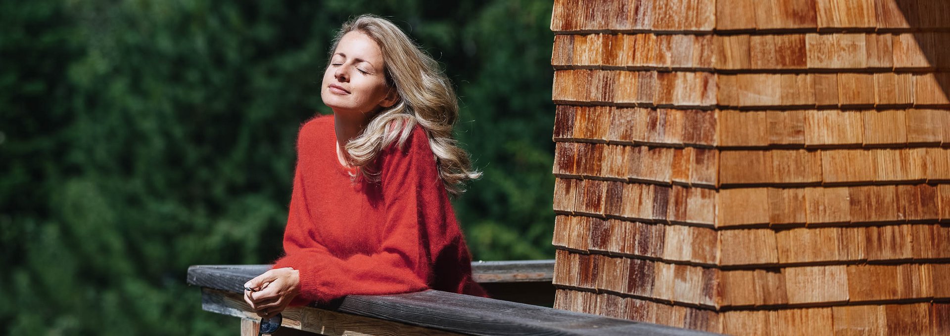 Genuss pur im Urlaub in Lech Eine Frau steht am Balkon und genießt die Sonne